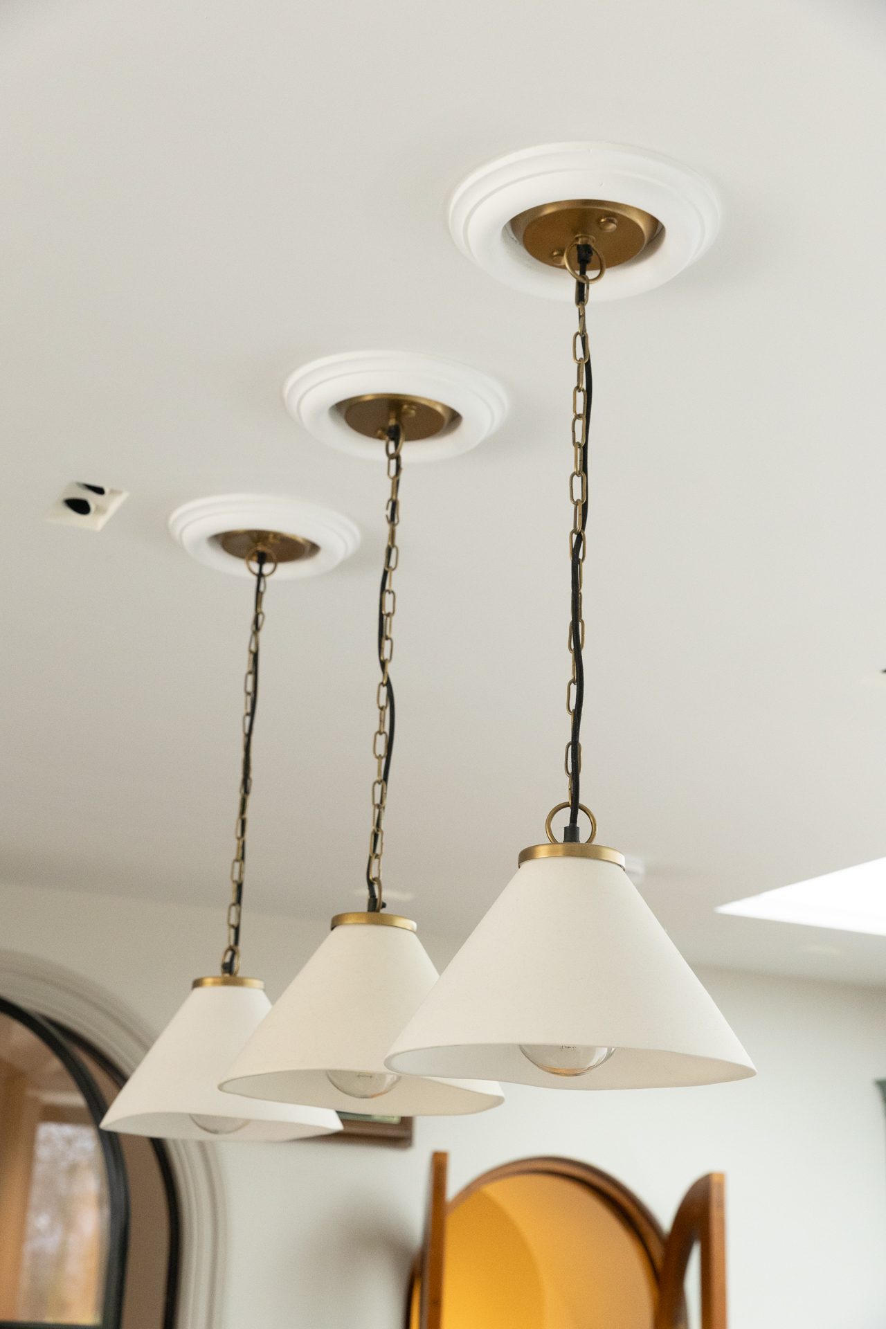 A trio of brushed brass pendants over a kitchen bar