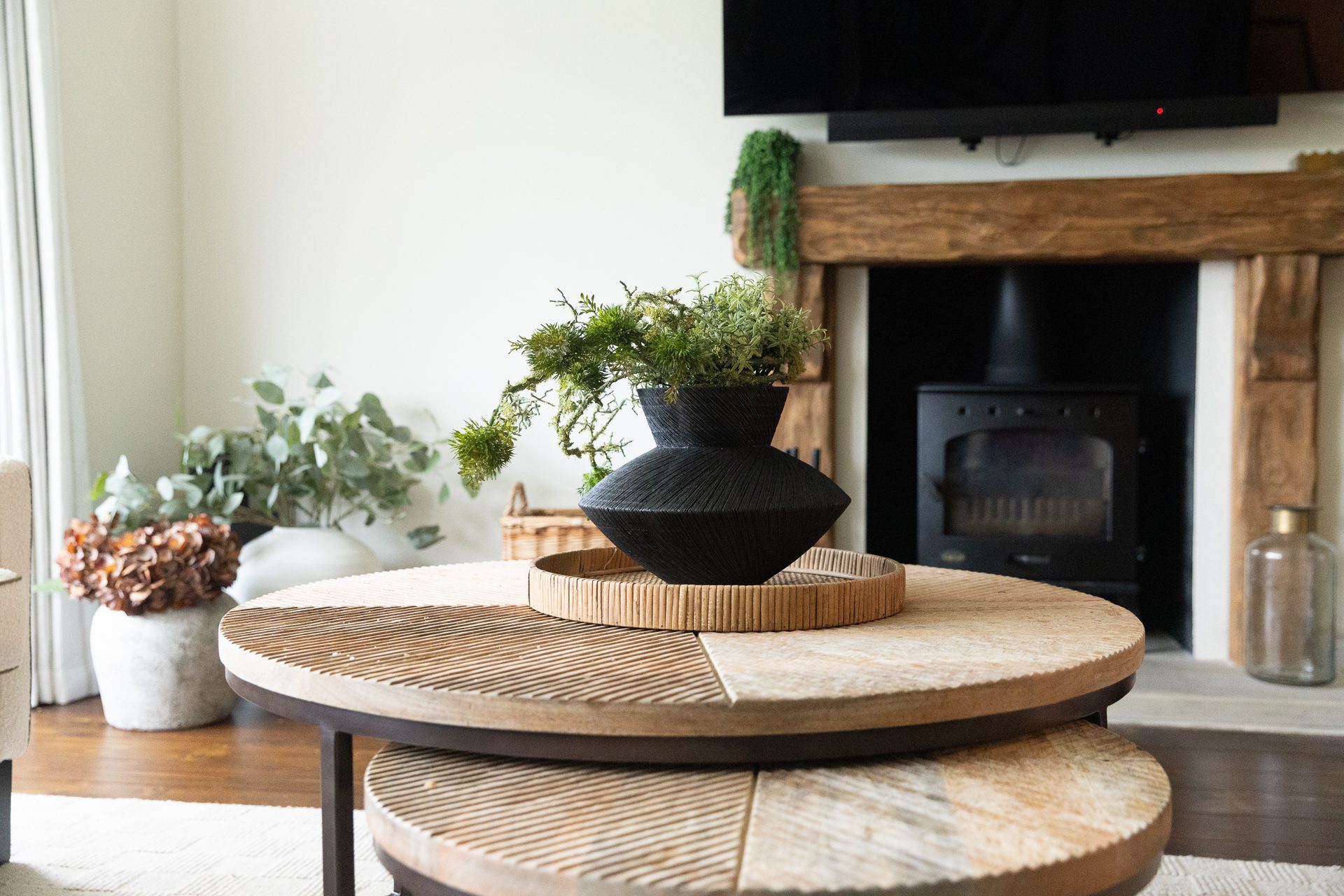 The pair of oak coffee tables at Bamburgh, dressed with a black vase of flowers, a stack of books and a stone pot of foliage