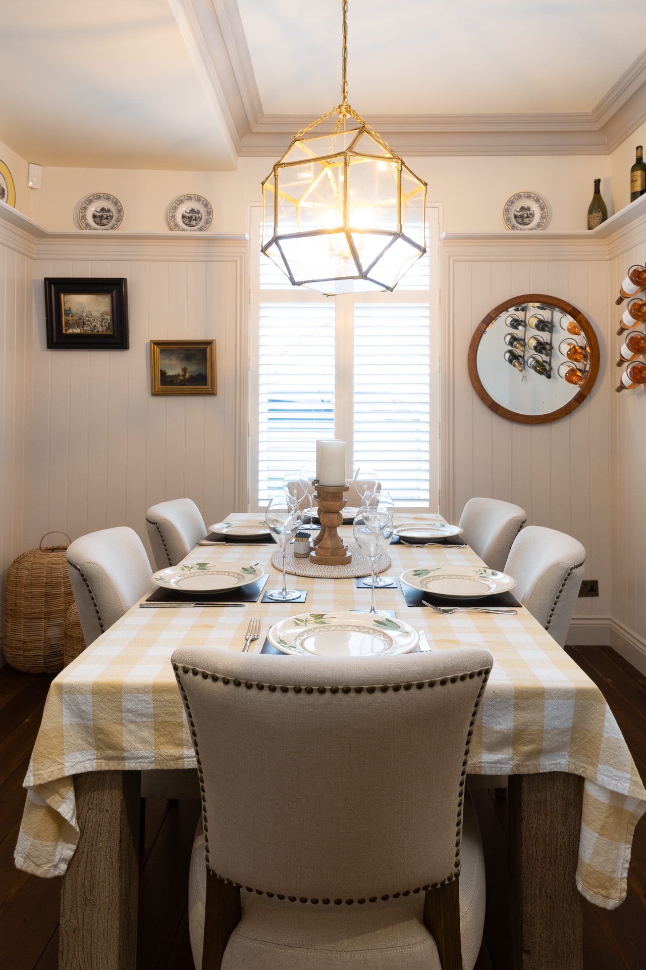 The Bamburgh dining room, panelled walls, gingham tablecloth set for six, a brass lantern pendant overhead