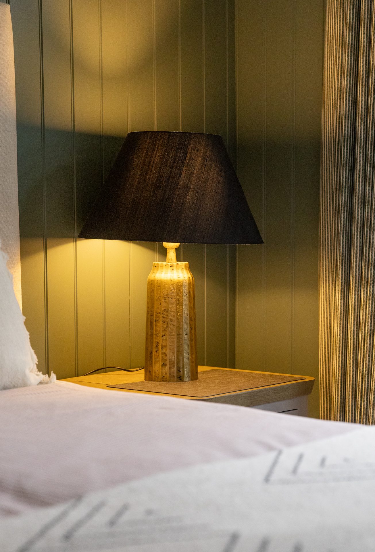 An amber ceramic bedside lamp in the Bamburgh master bedroom