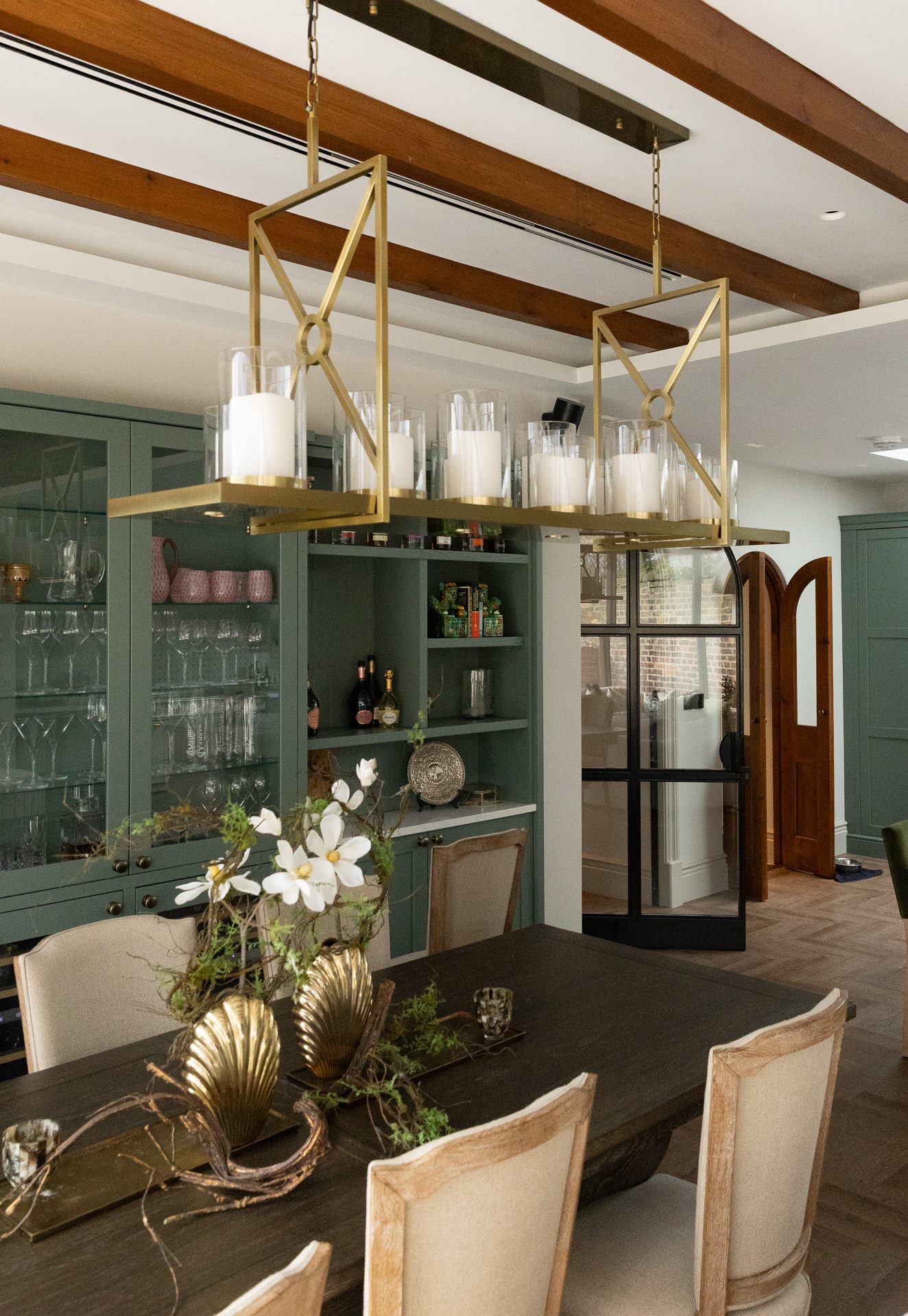 Dining area with brass geometric pendant and timber beams at Elmfield Road