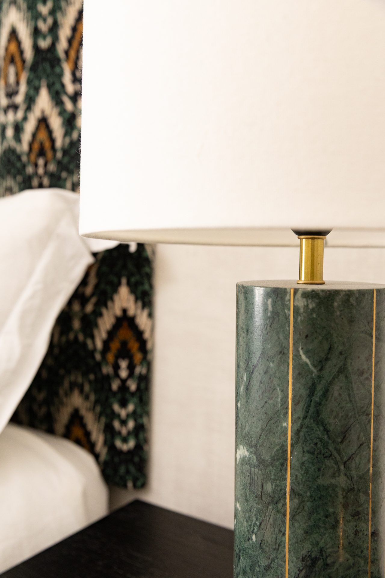 The master bedroom with an ikat patterned headboard, layered linens and soft natural light