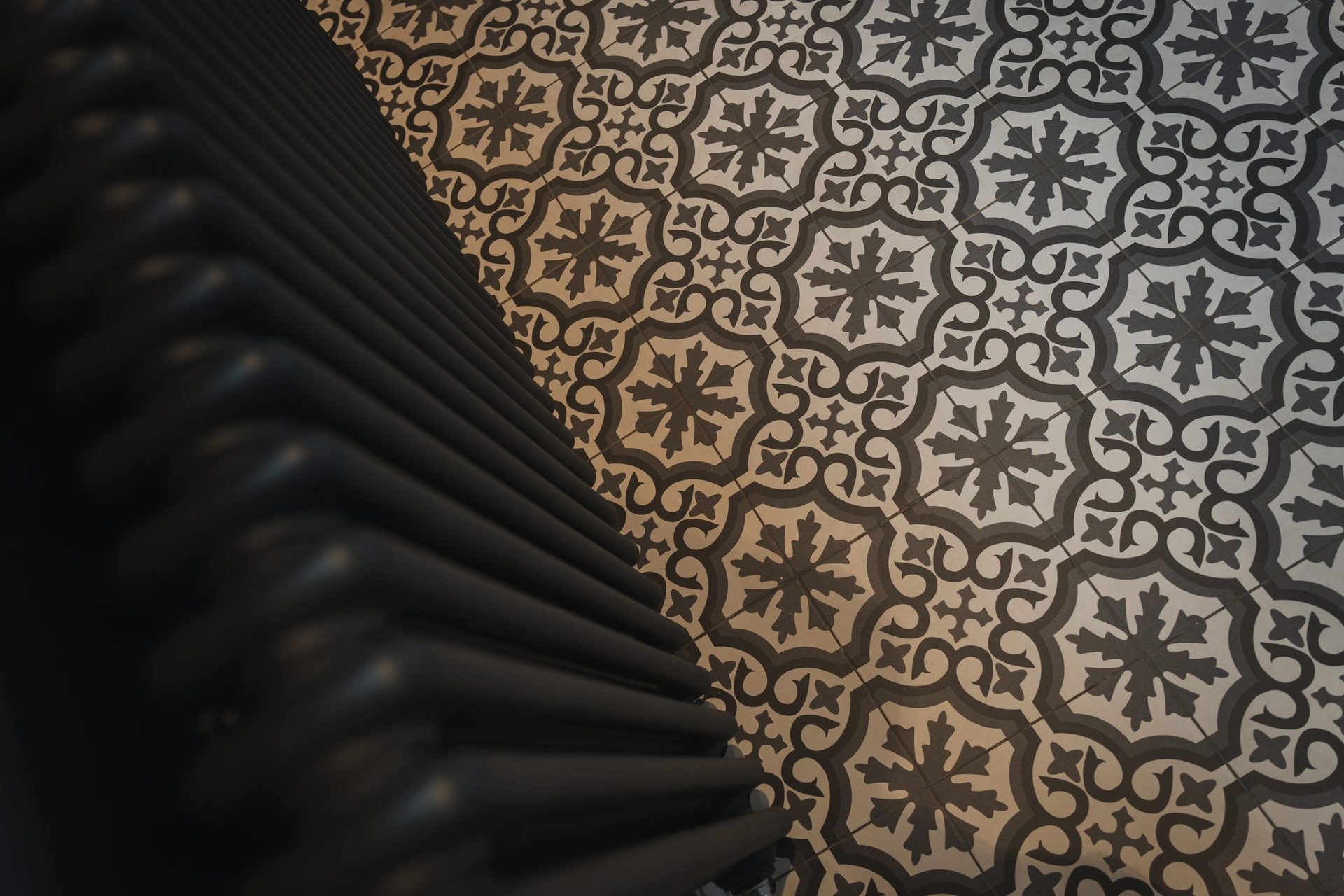 Detail of a black cast-iron radiator against the blue and cream encaustic floor tile