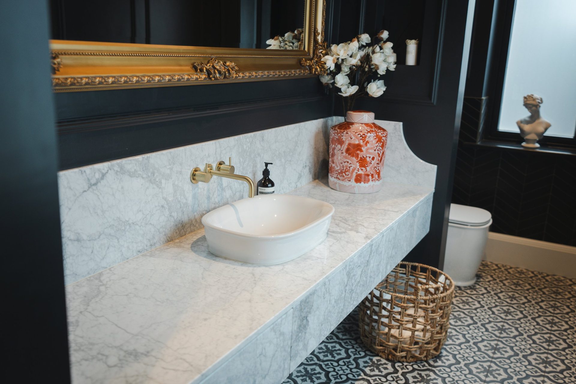 The Montagu W.C, a marble vanity, patterned tiled floor, black panelled walls, a porcelain ginger jar