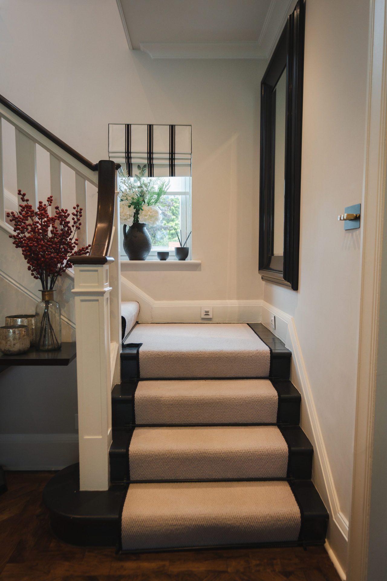 Looking down the staircase from part way up, the runner curving gently with the stair, the console visible below