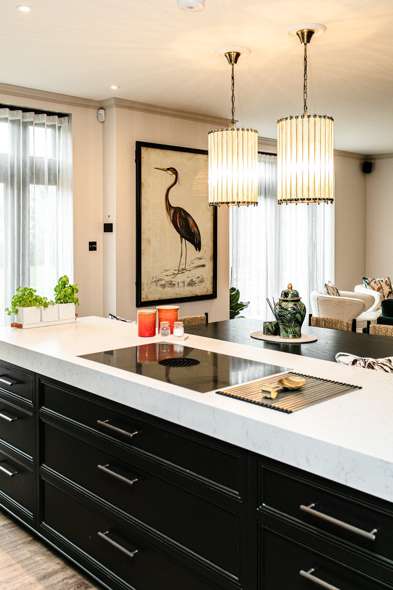The dining zone off the kitchen, round table with brass pendants overhead, dark cabinetry behind