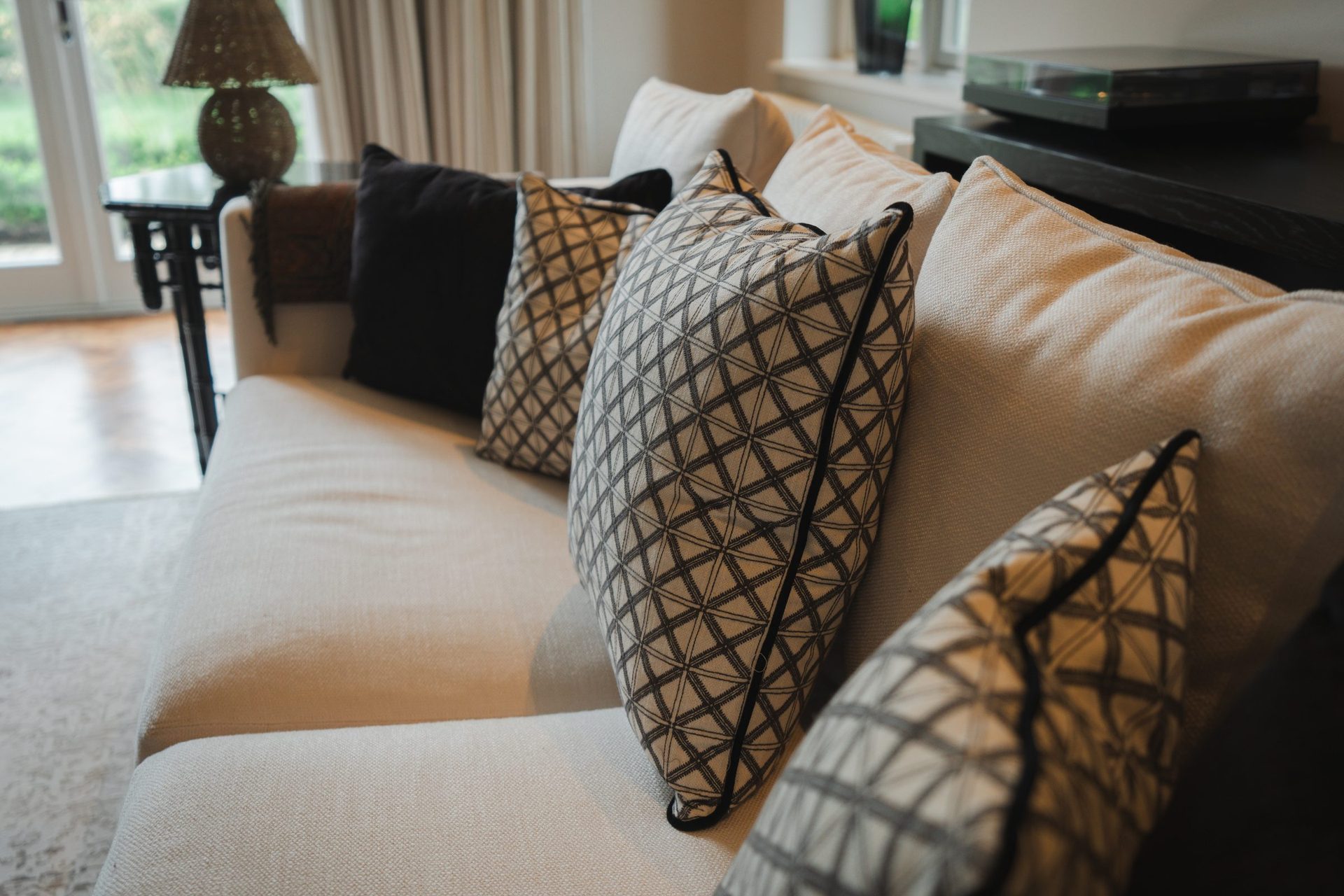 Close-up of the cream sofa with geometric black and cream cushions stacked along its length