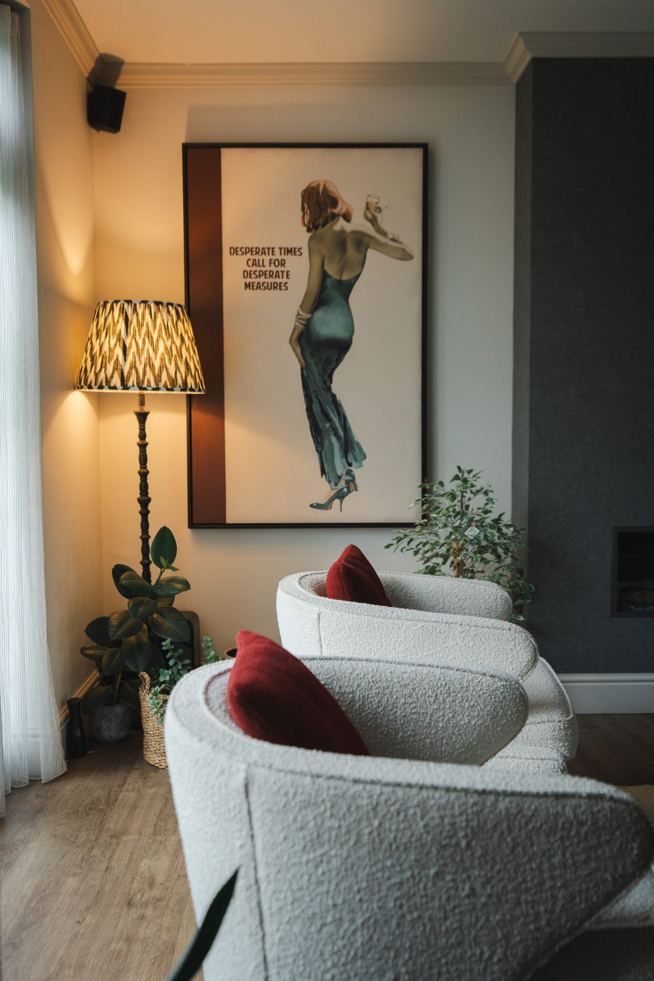 The sitting room in close, a pair of cream bouclé armchairs with cinnamon cushions, a floor lamp drawn in from the corner