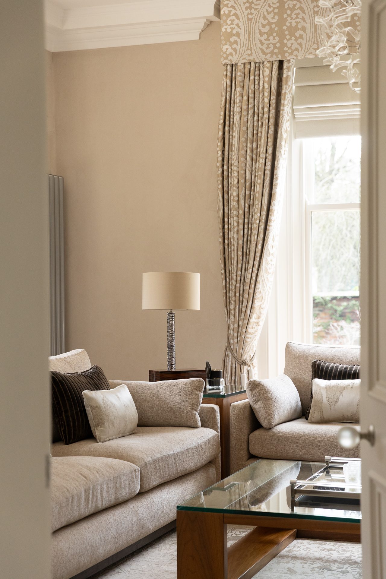 A Springfield interior glimpsed through a partly open doorway, a table lamp lit, patterned curtains at the window