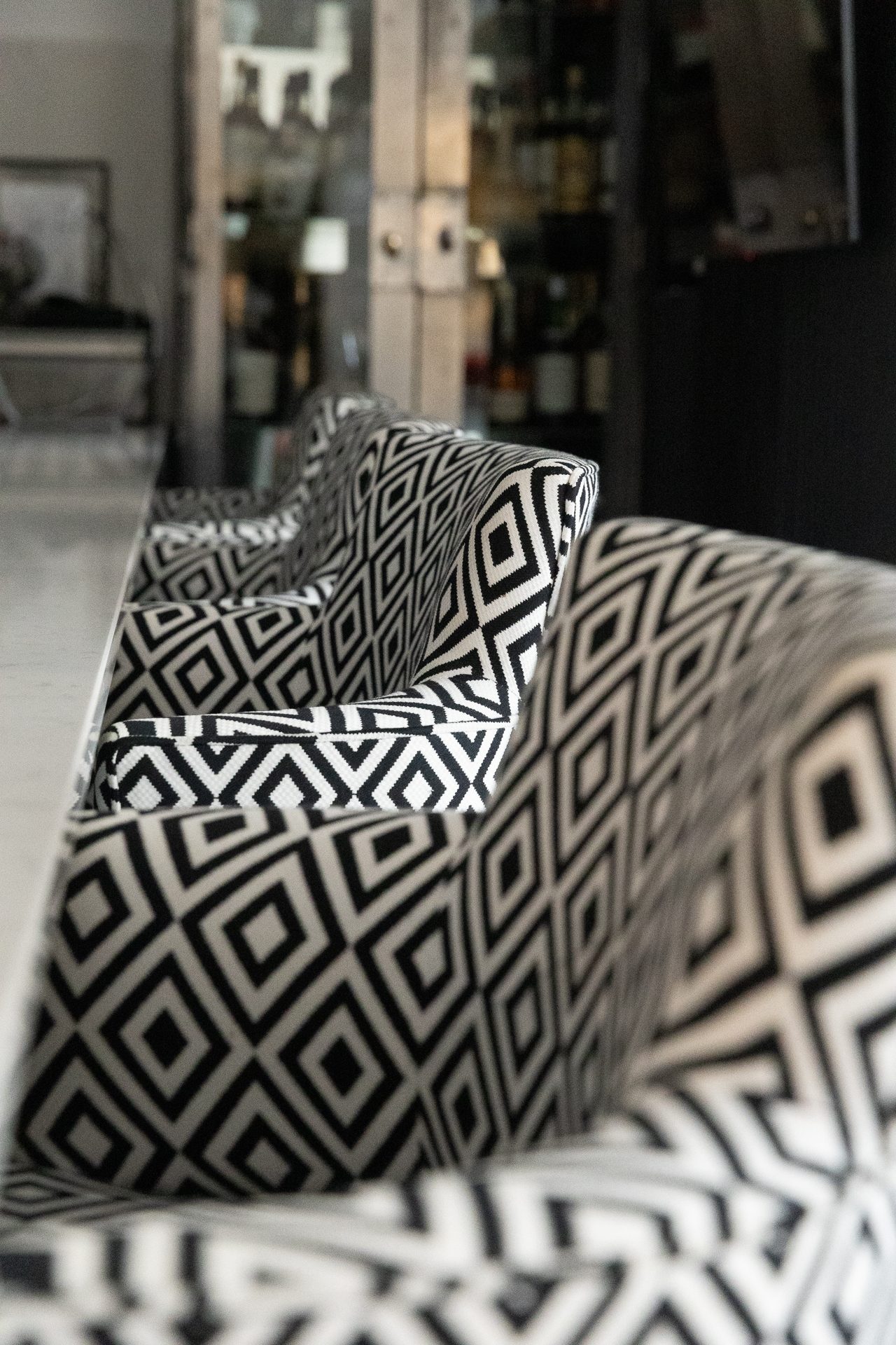 Diamond-weave upholstery on the Sycamore dining chairs, held tight against a blurred drinks cabinet beyond