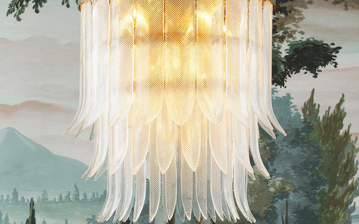 A statement Eichholtz chandelier with sculptural glass feathers in brass, hung in front of a classical Italianate landscape mural — sculptural lighting that anchors a room